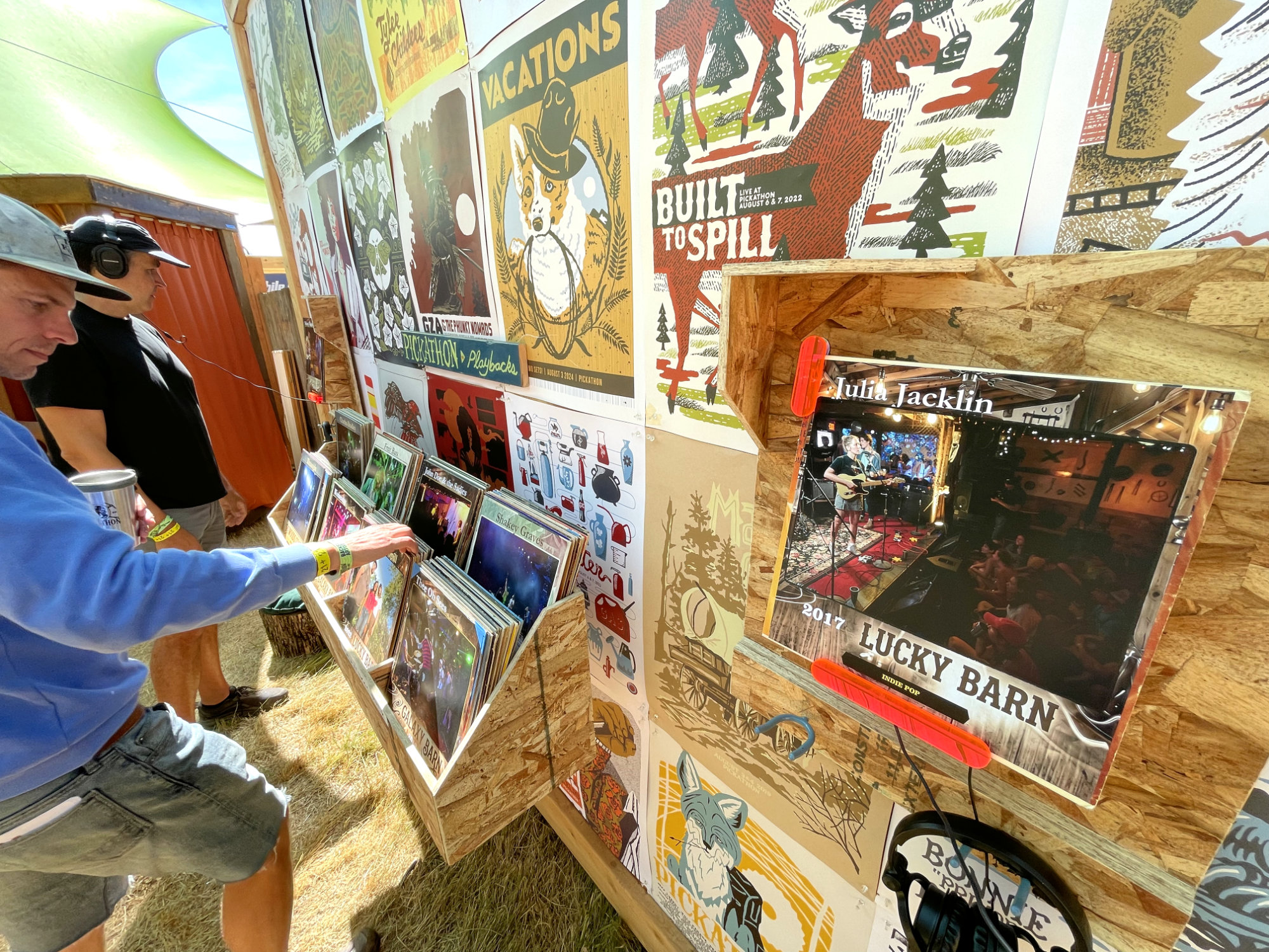 Two visitors browse the album crates while a large album cover for Julia Jacklin’s 2017 “Lucky Barn” set sits active in the listening station.